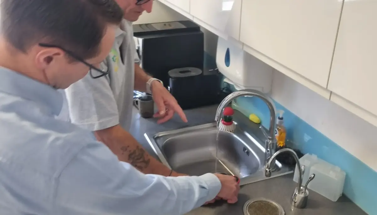 Learner checking water temperature at a tap during practical Legionella training
