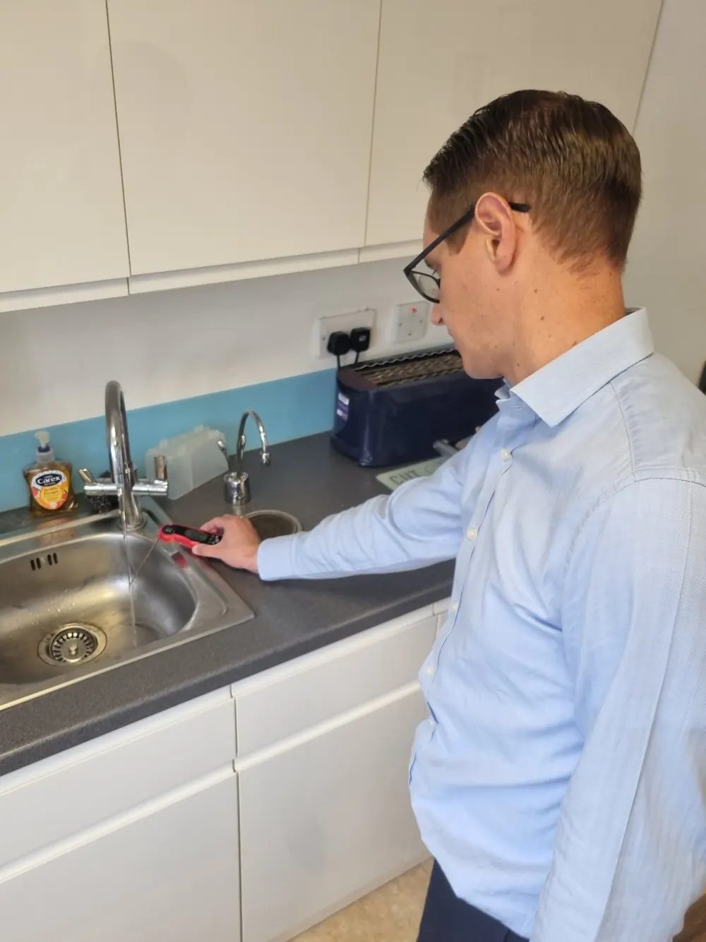 Practical Legionella training showing a water temperature check at a hot and cold water outlet